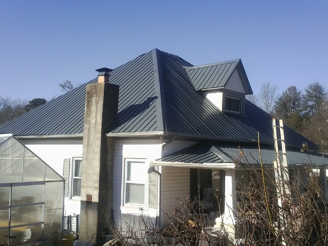 Dark blue standing seam metal roof on a white farmhouse with dormer — Slate & Tile Roof Repair by Roofing Brothers in Kauneonga Lake