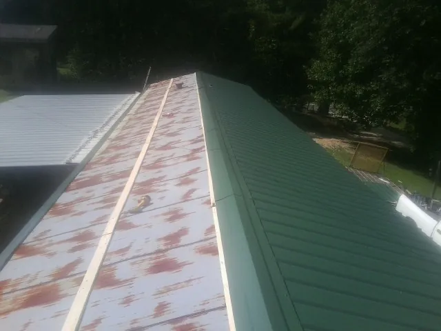 Old rusted panels beside newly installed green metal roofing — Wind Damage Roof Repair by Roofing Brothers in Kauneonga Lake