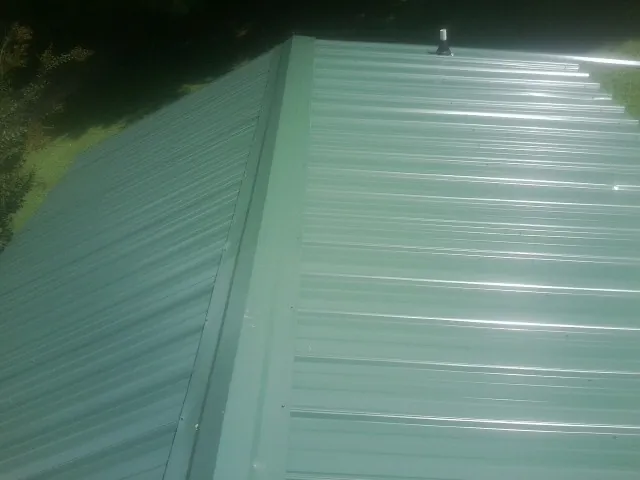 New green metal panels meeting at the ridge of a roof — Flat Roof Repair work by our crew in Kauneonga Lake