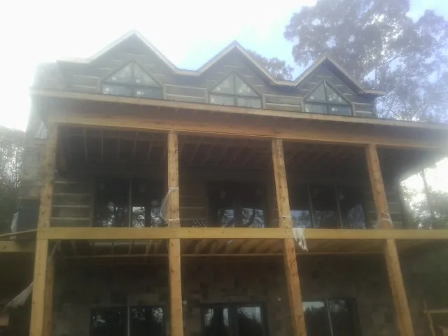Dormers and porch framing on a large log home under construction — Roof Coating work by our crew in Kauneonga Lake