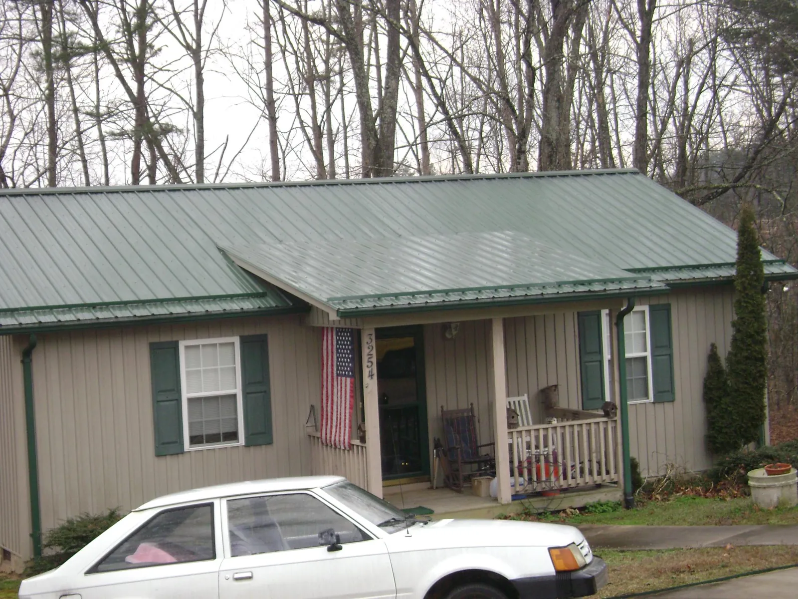 Green metal roof and front porch on a tan sided cottage in Kauneonga Lake