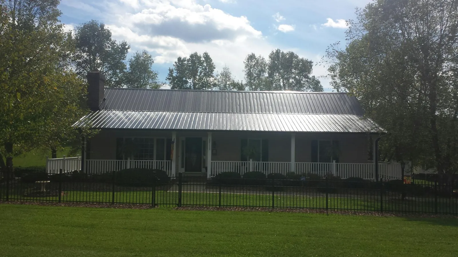 Gray metal roof on a brick ranch with a full width front porch — Gutter Guard Installation work by our crew in Kauneonga Lake