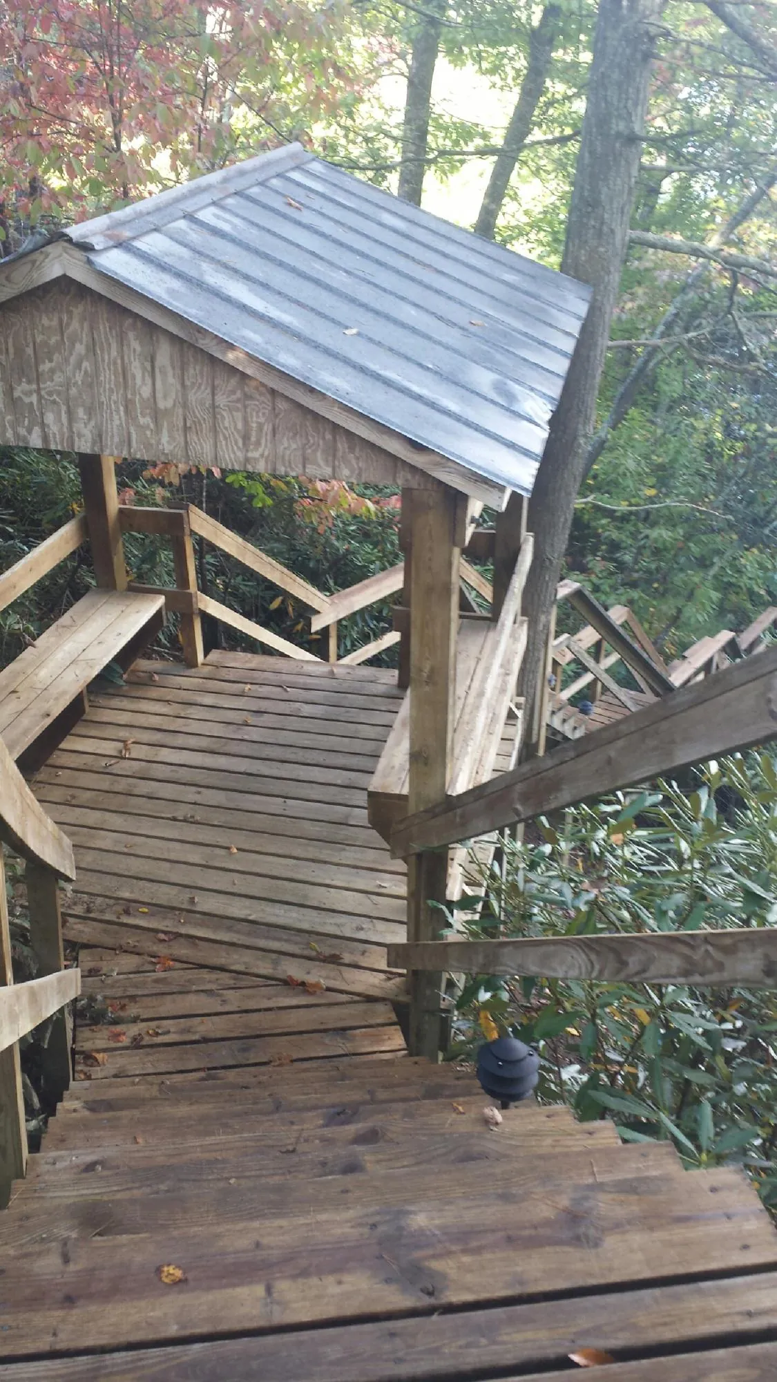 Metal roofed shelter over wooden steps on a wooded walkway — Skylight Repair & Installation work by our crew in Kauneonga Lake