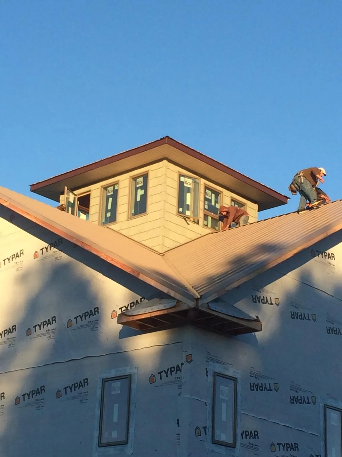 Roofers working around a rooftop cupola on a new metal roof at sunset — Roof Waterproofing in Kauneonga Lake by Roofing Brothers